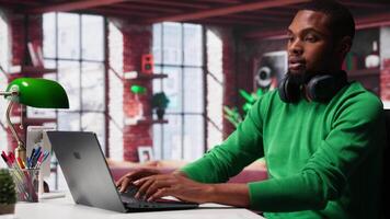 African american person at home extracting information on textbook, writing down data on notepad and identifying trends. Guy compiling analytical reports and taking notes. Camera A. video
