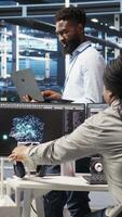 Vertical Portrait of cheerful data center engineer analyzing gear issues using node tree tools. Upbeat African american server hub specialist using AI visualization insights to optimize system health, camera A video