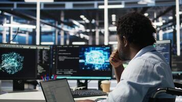 Server room admin with disability interprets machine learning generated data analytics graphs. IT professional in inclusive data center using artificial intelligence showing system metrics, camera A video