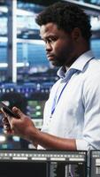 Vertical Data center technician uses node tree programming interface to identify equipment performance issues. Engineer reviews data analysis graph in server hub to minimize hardware failures, camera B video