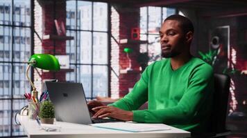 Man at home desk using laptop and checking emails displayed on screen, reading messages in inbox and sending replies. Young adult managing electronic correspondence, organizing folders. Camera A. video