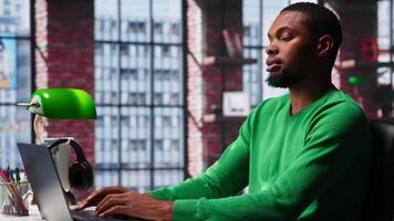 African american male teleworker completing spreadsheets on laptop, entering numerical data into cells and calculating totals. Guy using spreadsheet software functions. Camera A. video