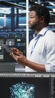 vertical dados Centro engenheiro usando tábua para interpretar dados analytics gráficos. servidor quarto trabalhador usando artificial inteligência exibindo sistema desempenho preditivo Métricas, Câmera uma video