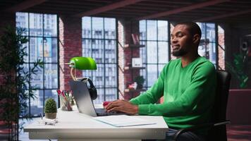 African american male teleworker completing spreadsheets on laptop, entering numerical data into cells and calculating totals. Guy using spreadsheet software functions. Camera B. video