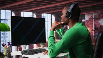Teleworker in home office watching business conference on PC, looking over statistics charts. African american remote employee in apartment looking at presentation graphs on computer. Camera B. video