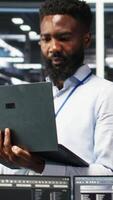 Vertical Happy data center admin uses node tree programming on laptop, doing high five with coworker. Smiling server farm worker greeting colleague, reviewing data analysis graph, camera B video