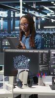 Vertical Portrait of upbeat server hub software developer using node tree software to optimize system health. Radiant data center staff member analyzing rigs issues using AI visualization, camera A video