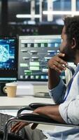 Vertical Admin in wheelchair and data center coworker working together using AI node tree software to minimize downtime. Server hub IT expert in disability and colleague using visual programming app, camera B video
