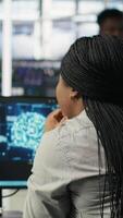 Vertical Data center software developer using artificial intelligence deep learning models to configure hardware. IT professional works on AI programming language in server farm, optimizing system, camera B video