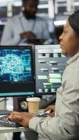 Vertical Data center admin does machine learning node tree programming, optimizing resource allocation. Server room worker uses predictive artificial intelligence visualization systems for maintenance, camera B video