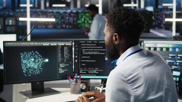 Server farm computer scientist interprets data analytics graphs. African american man in data center using artificial intelligence program showing predictive system metrics, camera A video