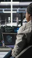 Vertical Server room IT expert using laptop to apply artificial intelligence technology minimizing system downtime. Technician using notebook to develop and deploy AI solutions optimizing equipment, camera A video