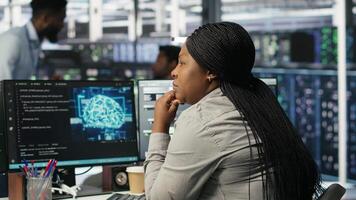 Data center staff member in office using AI deep learning algorithms to analyze datasets. African american woman in server room using artificial intelligence neural networks, camera B video