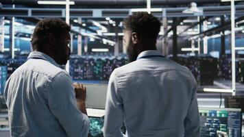Server hub engineering team interprets data analytics graphs. Teamworking data center colleagues using artificial intelligence program showing predictive system metrics, camera A video