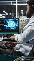 Vertical Engineer using wheelchair in data center using AI node tree software to minimize system downtime. Server hub worker in disability using visual programming to monitor performance, camera A video