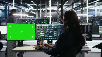 Data center technician using node tree software on green screen PC to analyze datasets. Server room worker using visual programming tools on chroma key computer to improve gear performance, camera A video