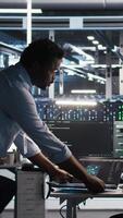 Vertical Server hub team leader and worker using node tree software to optimize system health. Data center manager supervising IT expert analyzing infrastructure issues using AI visualization, camera A video