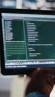 Vertical Close up of data center software developer checking code on tablet used to update equipment. Server hub expert using programming language script on device to do maintenance, camera A video