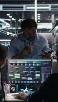 Vertical Data center coworkers doing brainstorming, using node tree software to analyze datasets. Server room teamworking colleagues using visual programming tools to improve gear performance, camera A video