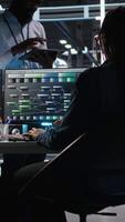 Vertical Server hub manager talking with programmer using node tree software to optimize system health. Data center supervisor overseeing IT expert analyzing equipment issues using AI visualization, camera A video
