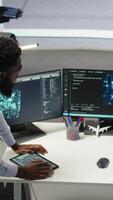 Vertical Technician in wheelchair and data center manager using AI node tree software to minimize system downtime. Server hub employee in disability and team leader using visual programming tool, camera A video