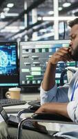 Vertical Data center computer scientist in wheelchair using AI node tree software to minimize system downtime. Server hub employee in disability using artificial intelligence visual programming tool, camera B video