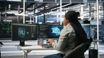 Data center software developer using artificial intelligence deep learning models to configure hardware. IT professional works on AI programming language in server farm, optimizing system, camera A video