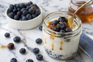 glass jar of organic yogurt topped with fresh blueberries and honey, creating delicious and healthy snack. vibrant colors and textures make it visually appealing photo
