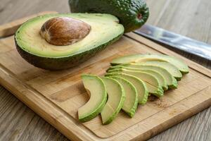 Fresh organic avocado sliced on wooden cutting board, showcasing its creamy texture and vibrant green color. Perfect for healthy meals and snacks photo