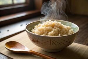 steaming bowl of organic rice sits beside wooden spoon, evoking warmth and comfort in cozy setting. natural light enhances inviting atmosphere photo