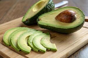 Freshly sliced organic avocado on wooden cutting board, showcasing its creamy texture and pit. Perfect for healthy meals and snacks photo