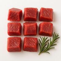 Raw Beef Cubes Arranged in a Grid with Fresh Rosemary on White Background for Cooking Preparation or Butcher Display photo