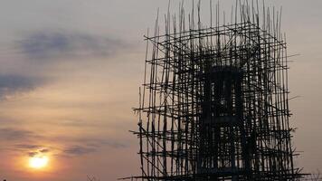 A scaffolding structure silhouetted against sunset sky, showcasing intricate wooden b photo