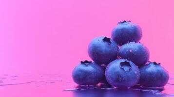 Colorful blueberries stacked with water droplets against a vibrant pink background in a creative setup photo