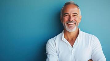 Smiling man in casual attire stands with arms crossed against a blue background photo