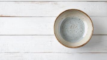 Ceramic bowl filled with clear water resting on weathered wooden table at home during bright daylight photo