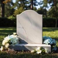 A tombstone sits in the grass with flowers photo