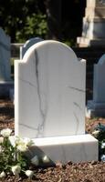 A white marble tombstone with flowers in front of it photo