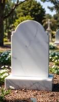 A white marble tombstone sits in a cemetery photo