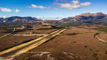 Aerial view of landing strip in the foreground and mountains in the background photo