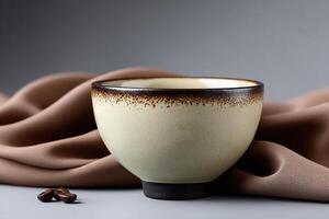 Ceramic tea cup with light glaze displayed on fabric background with coffee beans photo