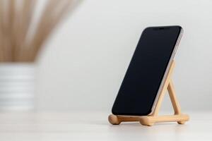 Smartphone displayed on a wooden stand with a modern background in a bright setting photo
