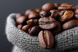 Rich dark roasted coffee beans spilling from a textured burlap sack photo