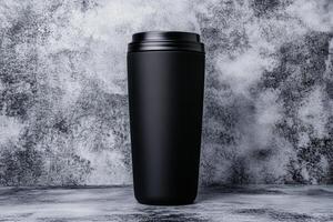 Stylish black travel mug on a textured grey background for on-the-go sipping needs photo