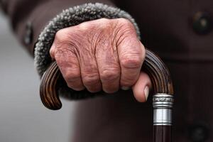 Elderly hand gripping a cane in cool weather while wearing a warm coat photo