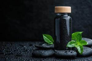 Black bottle filled with fine charcoal powder and stones arranged with green leaves photo