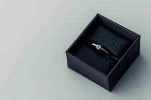 Elegant diamond ring displayed in a black box on a soft surface photo