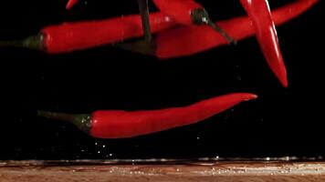Red chili peppers fall on the table. Filmed on a high-speed camera at 1000 fps. High quality FullHD footage video