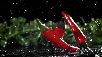 Red chili peppers fall on the table. Filmed on a high-speed camera at 1000 fps. High quality FullHD footage video