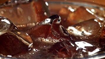 A glass of cola with ice. Splashes on the surface. Filmed on a high-speed camera at 1000 fps. High quality FullHD footage video